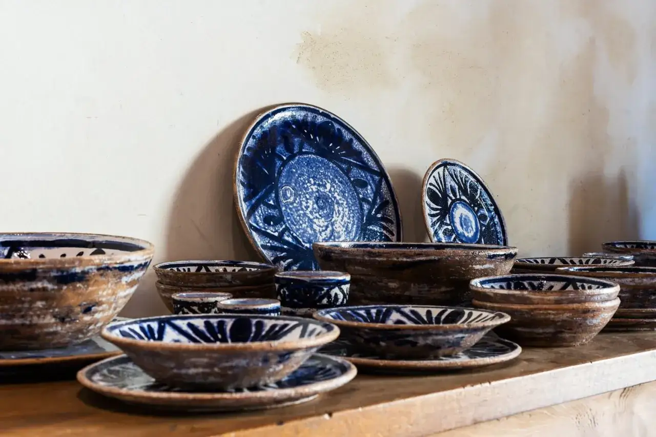 Ceramiche artigianali toscane con decori blu cobalto su fondo grezzo. Piatti e ciotole che raccontano la tradizione.