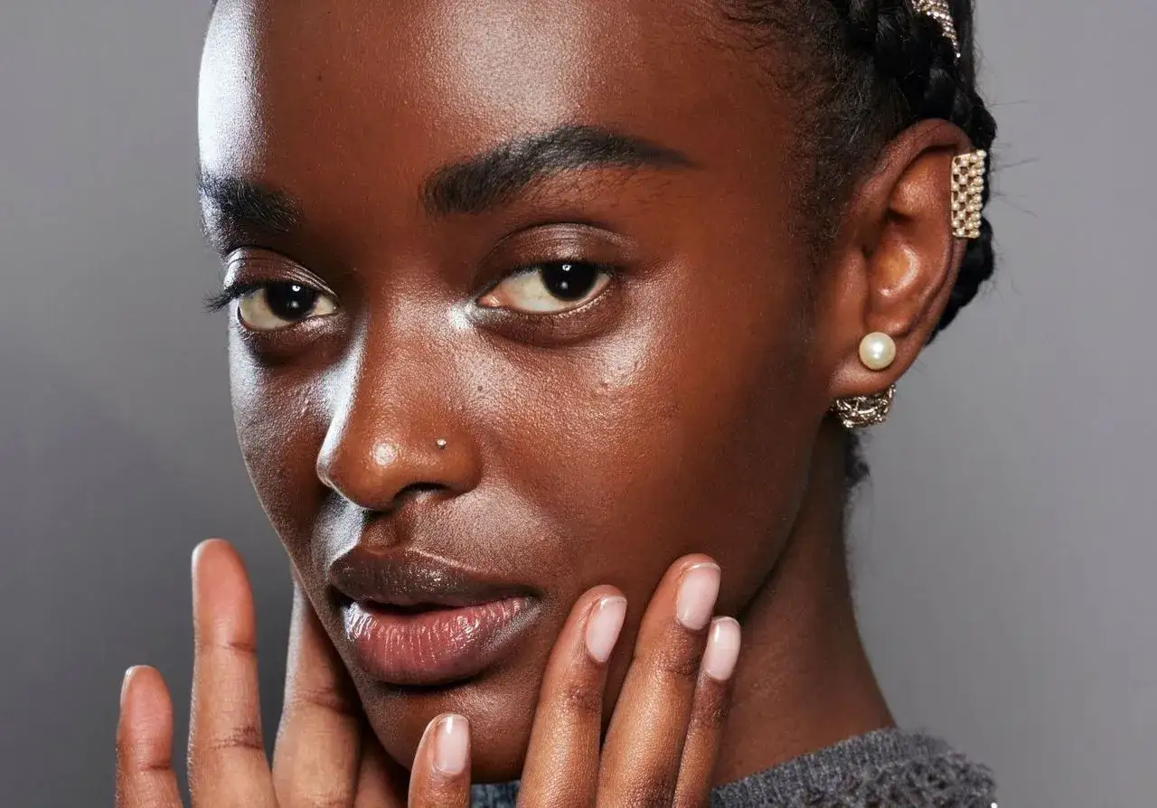 Un visage sublimé par le dermaplaning, peau lisse et éclatante. Bijoux d'oreilles sophistiqués.