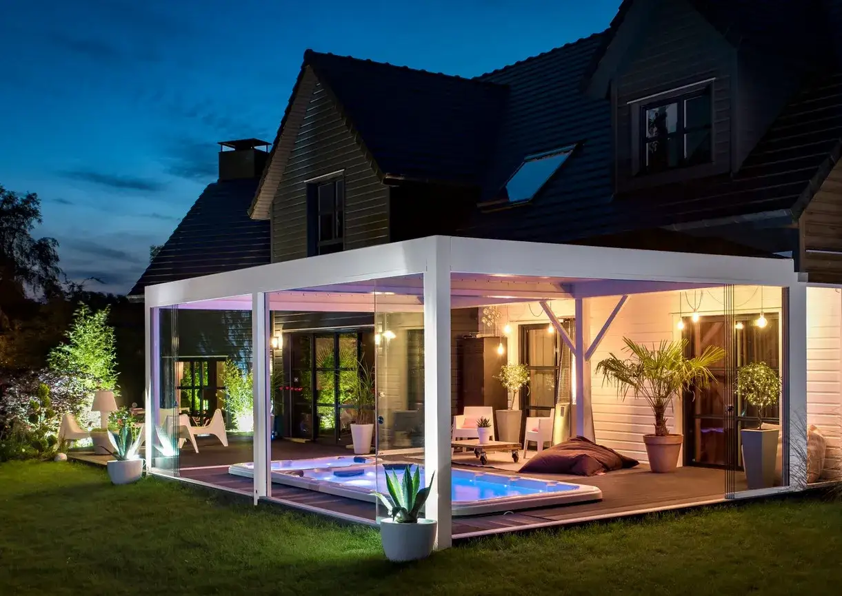Un luxueux spa sous pergola, illuminé par des lumières d'ambiance, invite à la détente dans un jardin paisible.