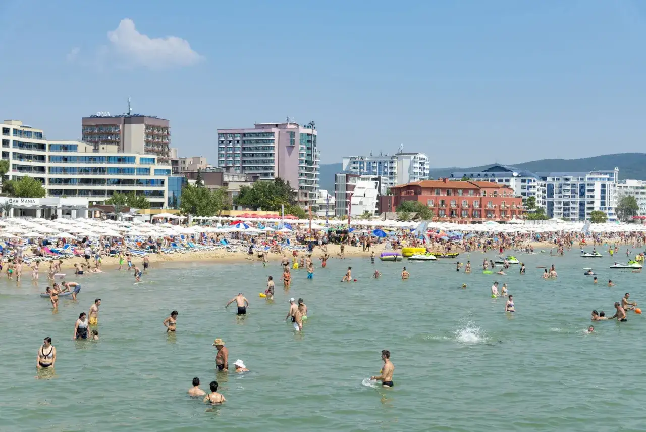 Tłoczna plaża w Bułgarii, ludzie kąpią się i opalają. W tle hotele i budynki, idealne miejsce na wakacje z euro.