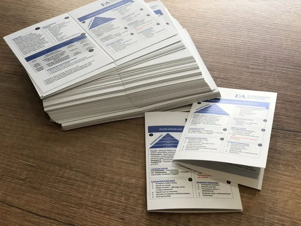 Stos kartek z materiałami szkoleniowymi, idealny surowiec dla drukarni. Na kartkach widnieją schematy i listy dotyczące technik sprzedaży.
