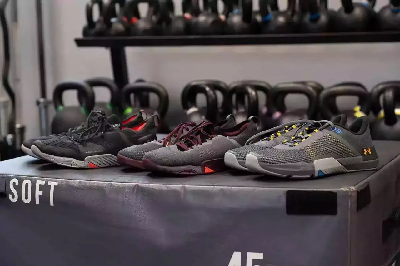 Wybierasz jakie buty do crossfitu? Cztery pary sportowych but&oacute;w treningowych, w tym czarne, bordowe i szare, stoją na skrzyni treningowej.