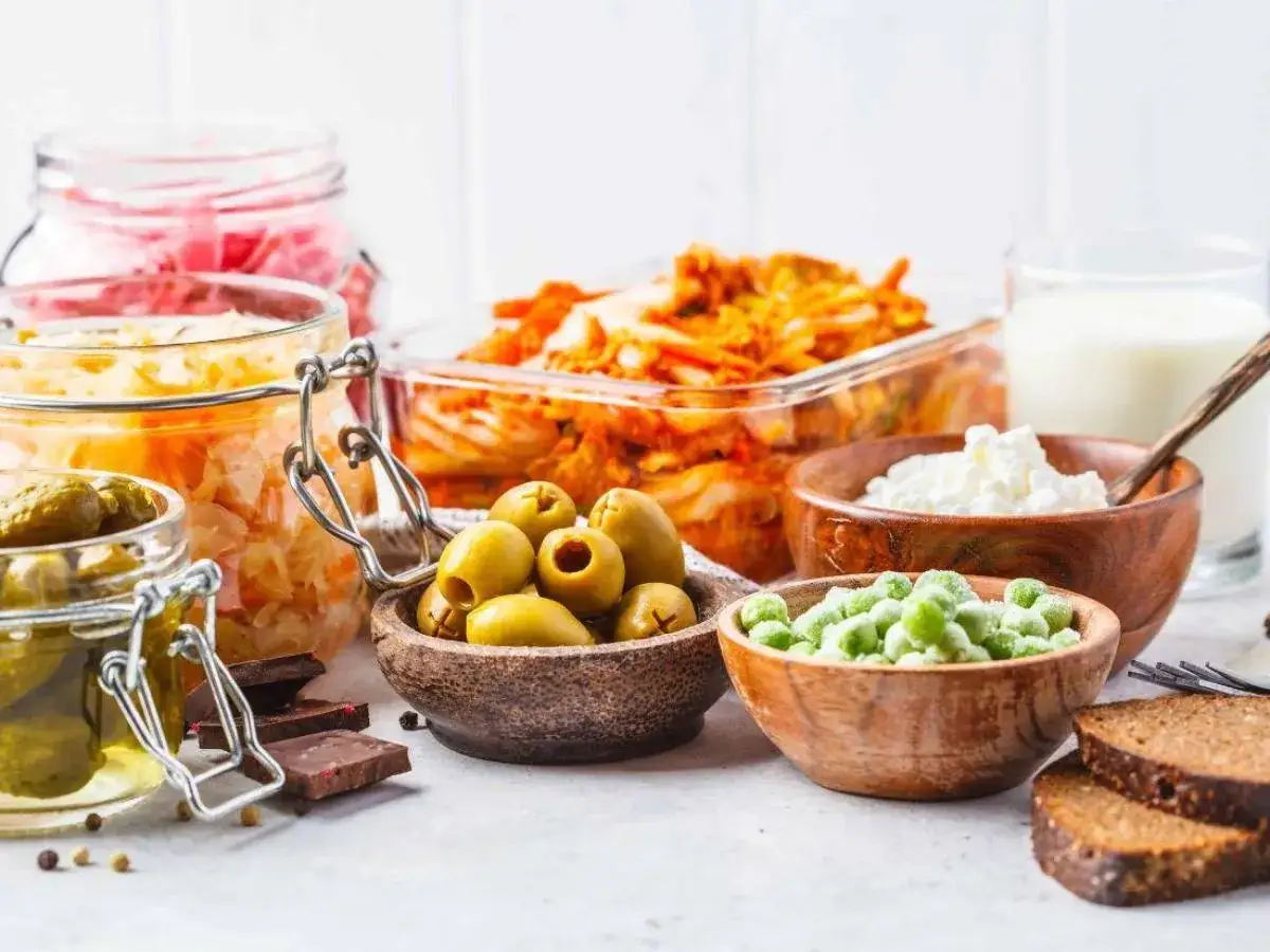 Une sélection d'aliments fermentés : choucroute, kimchi, cornichons, olives, yaourt, lait, pois et pain de seigle.