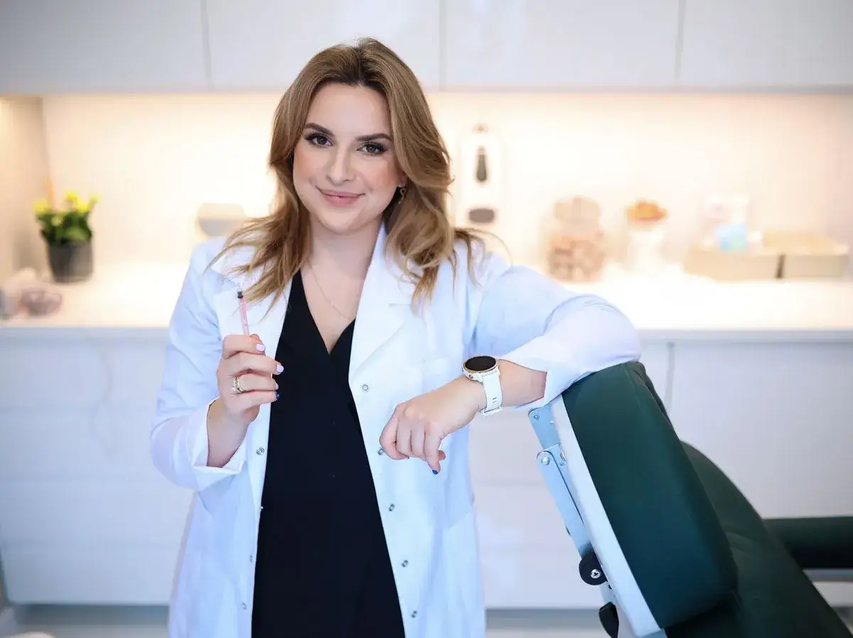 Lekarka z zastrzykiem w dłoni, uśmiecha się, opierając o fotel. Czy botox jest bezpieczny? Odpowiedź znajdziesz w gabinecie.