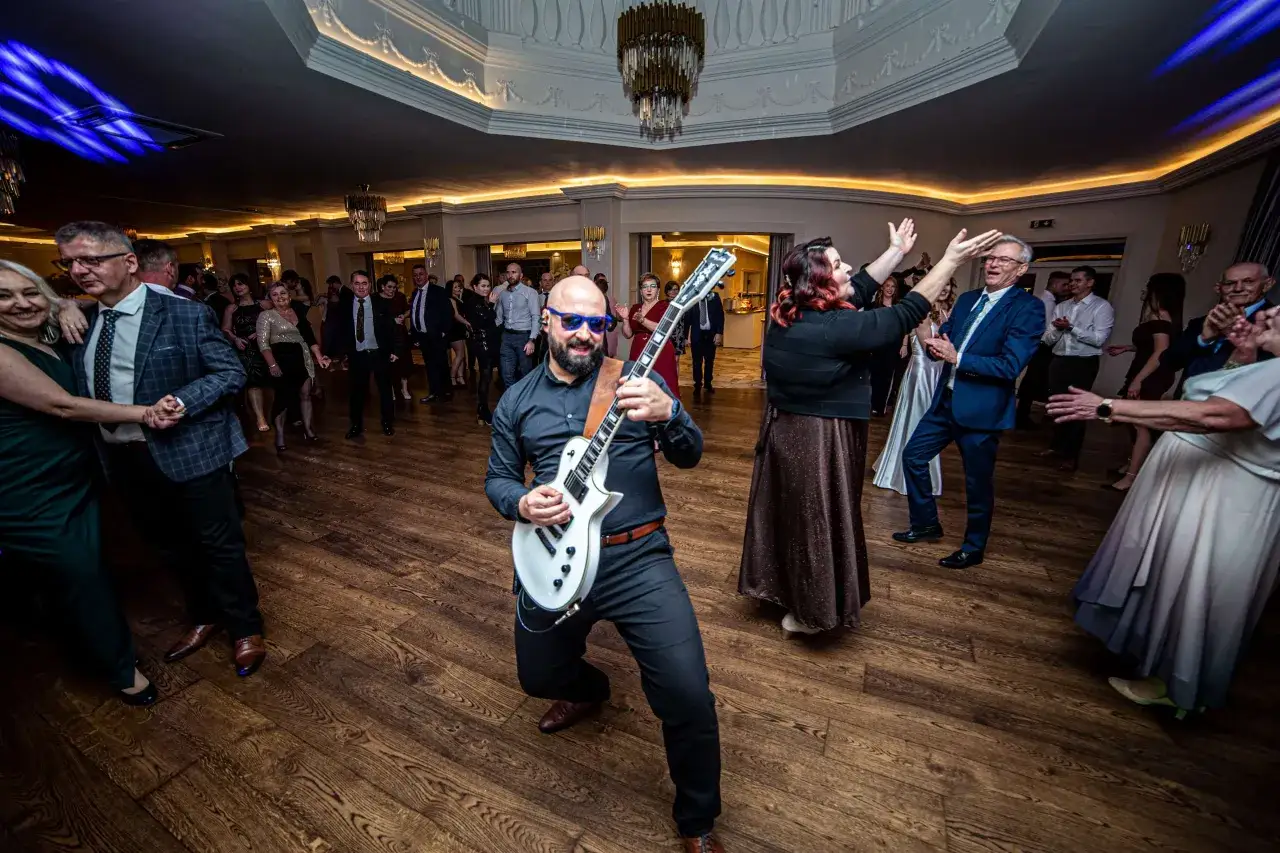 Wesele w pełni! Goście tańczą w rytm świetnych piosenek na wesele, a gitarzysta dodaje energii.