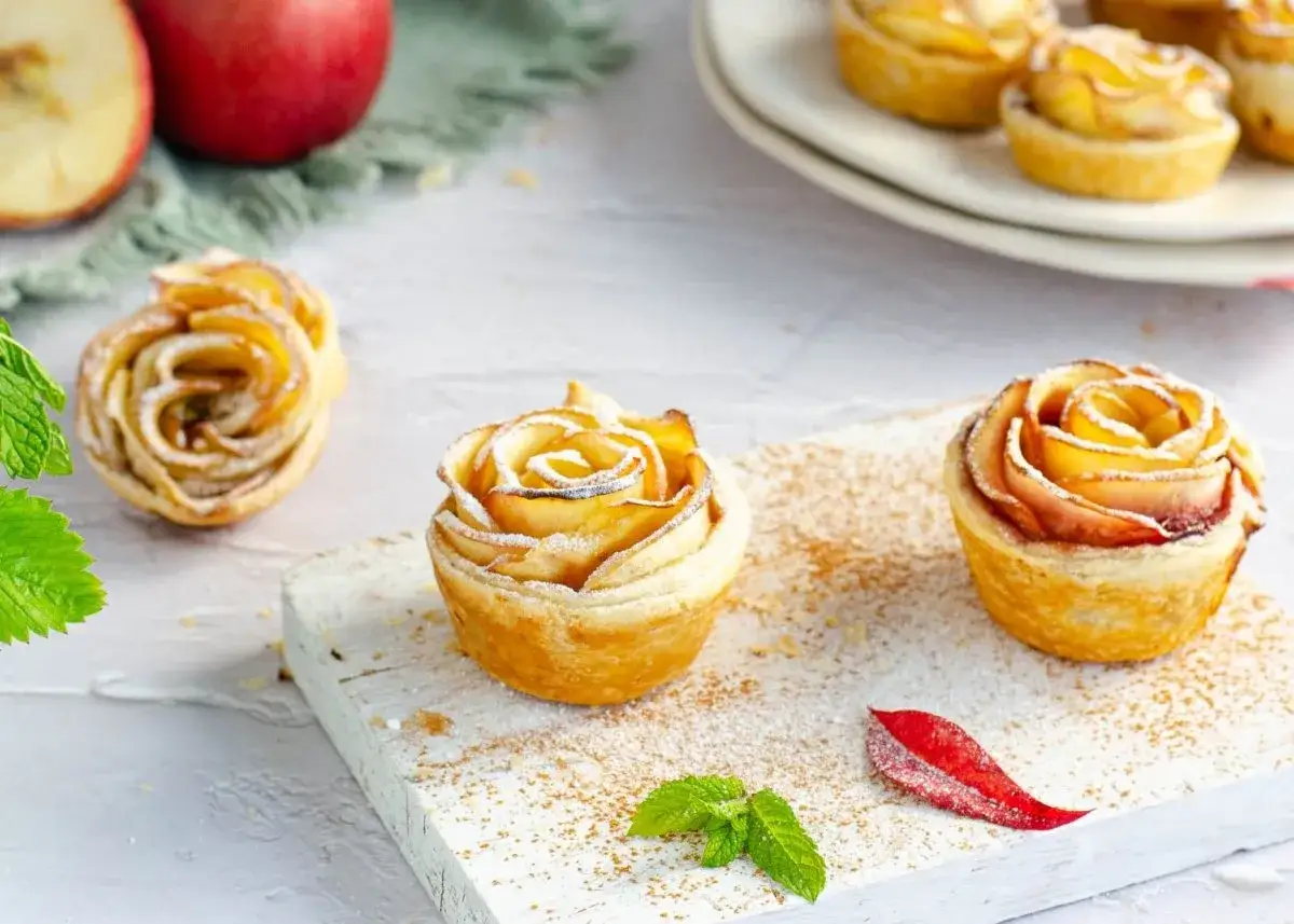 Deliciosas rosas de manzana cubiertas de azúcar glas, con hojas de menta y canela espolvoreada.
