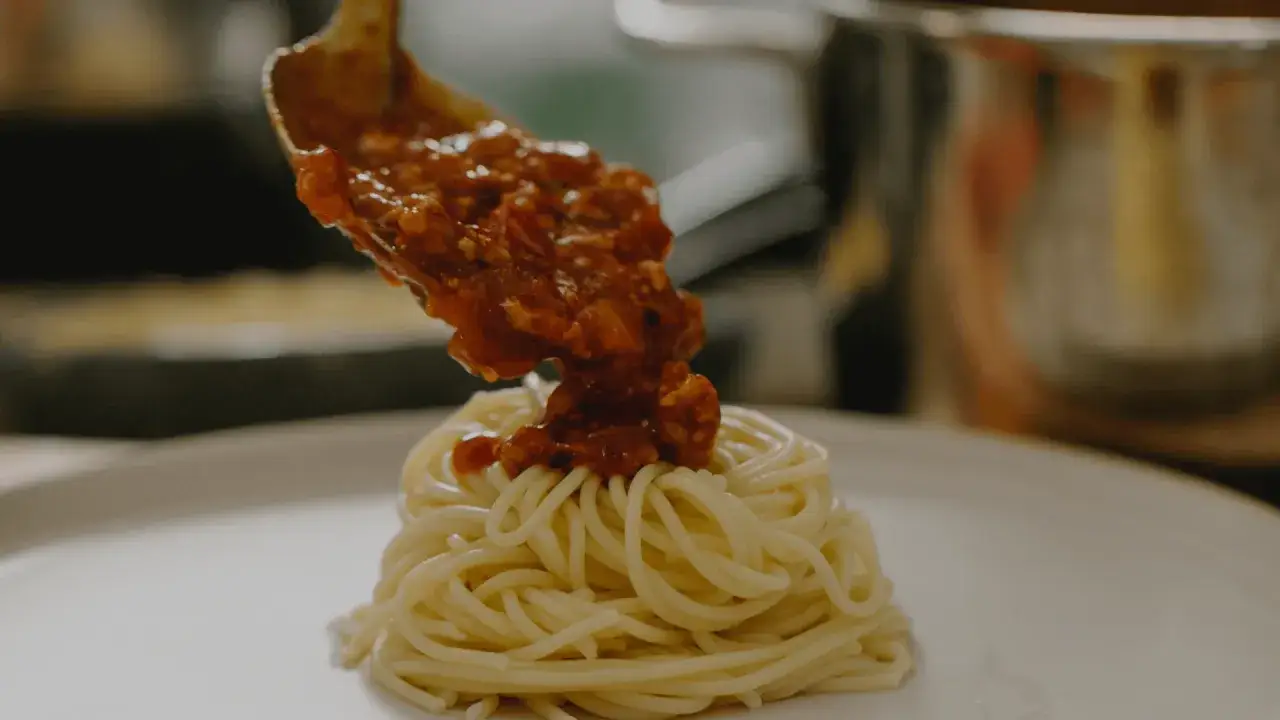 En sked med mustig k&ouml;ttf&auml;rss&aring;s toppar en h&ouml;g med spaghetti. Perfekt f&ouml;r ett klassiskt bolognese recept.