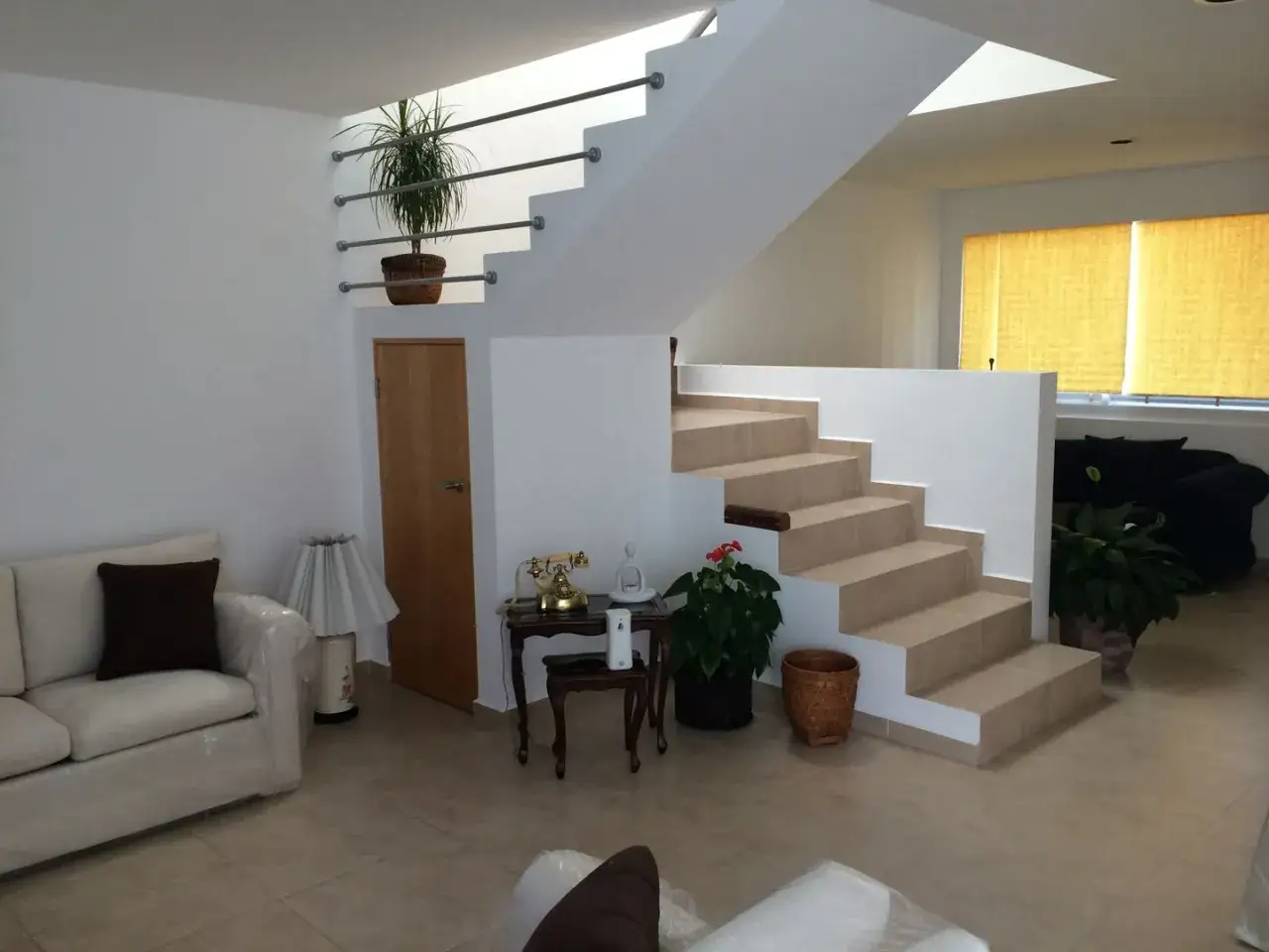 Un acogedor aseo bajo escalera con una planta decorativa y un teléfono antiguo.
