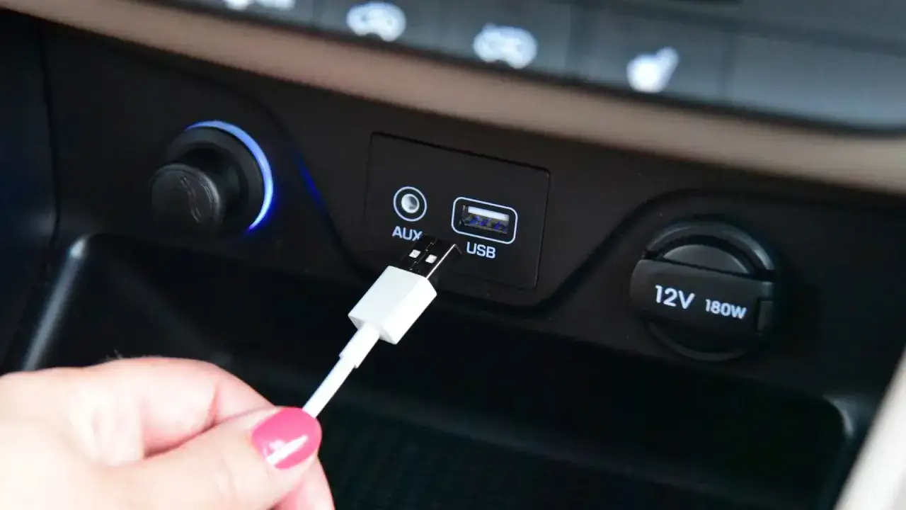 Mano inserisce cavo USB nella porta dell'auto per collegare il telefono allo stereo.