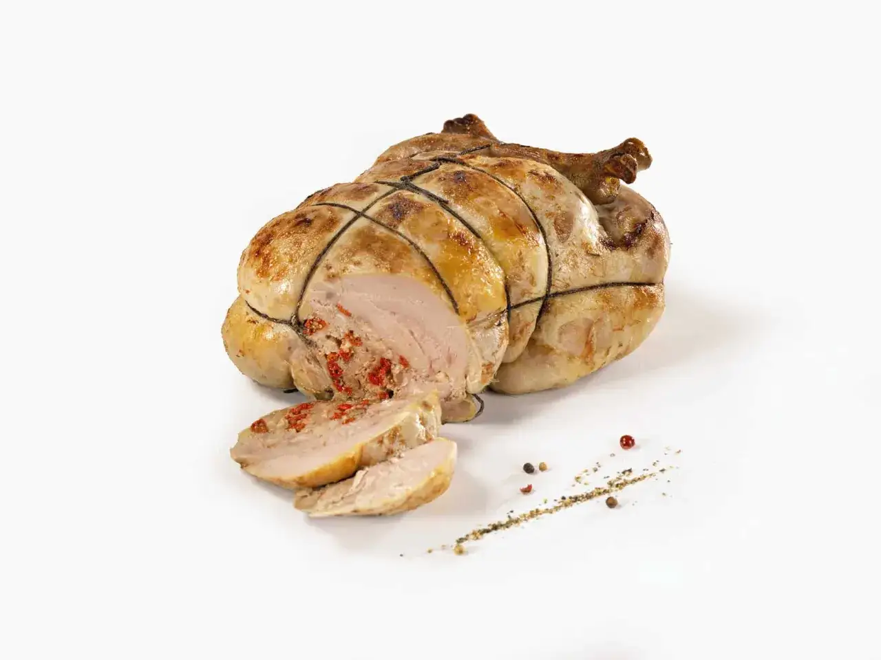 Une pintade au four, dor&eacute;e et savoureuse, est tranch&eacute;e, r&eacute;v&eacute;lant une farce rouge. Des grains de poivre pars&egrave;ment la pr&eacute;sentation.