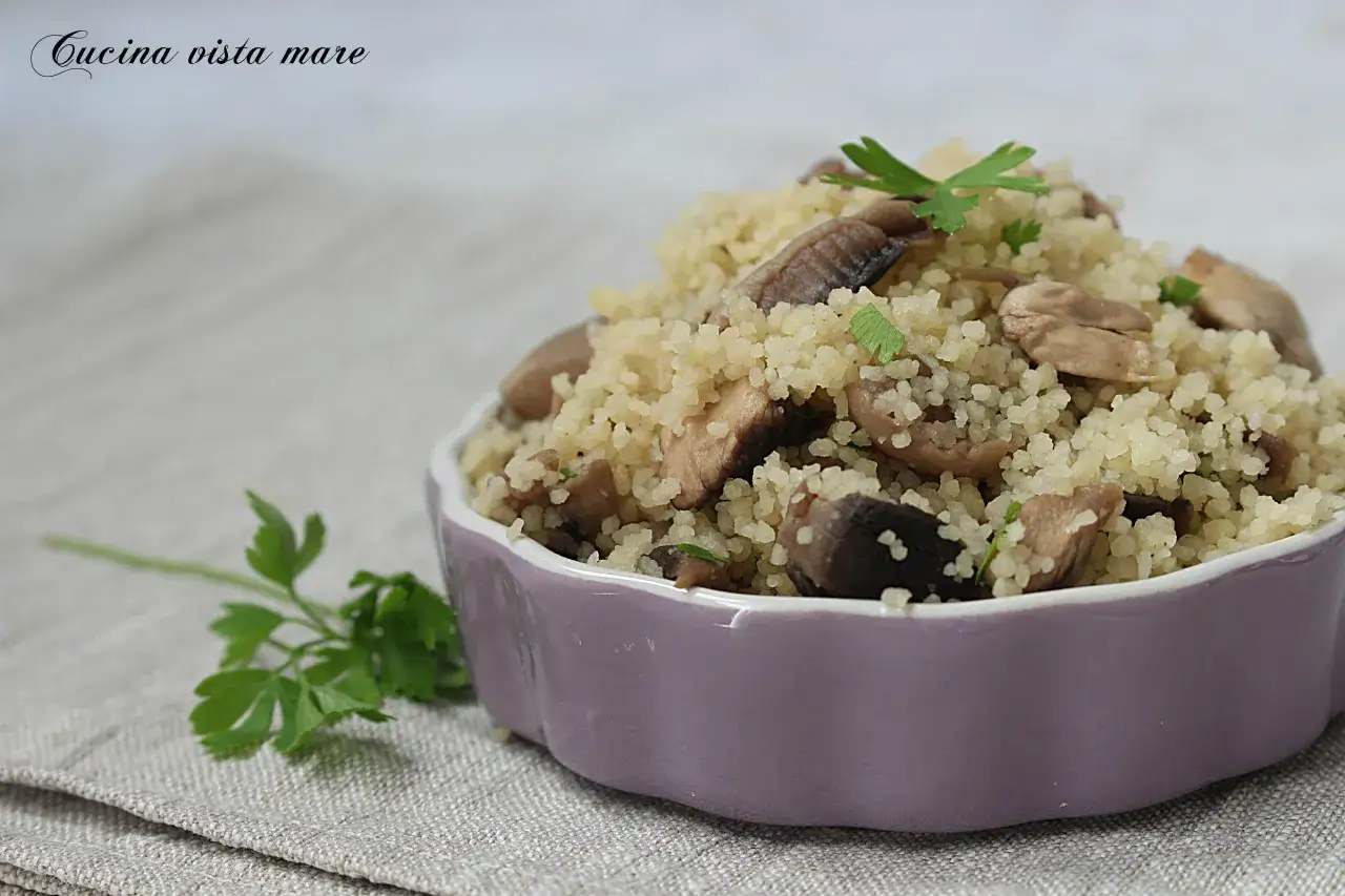 Un saporito cous cous con funghi e prezzemolo, servito in una ciotola viola.