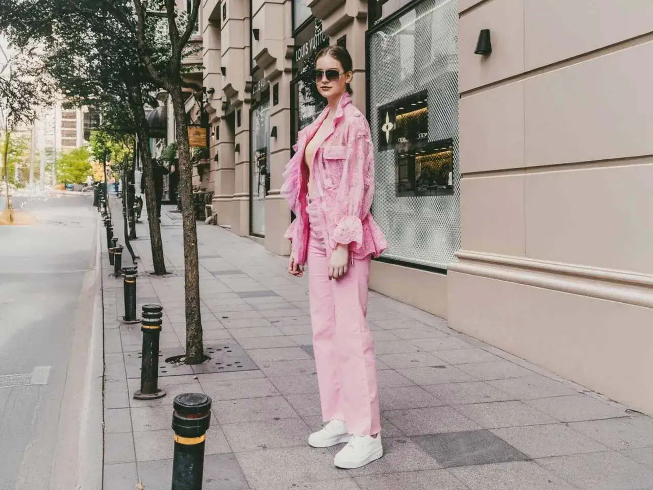 Ein Model pr&auml;sentiert, wie man eine **pinke Hose kombinieren** kann: mit einem passenden pinken Spitzen-Blazer und wei&szlig;en Sneakern.