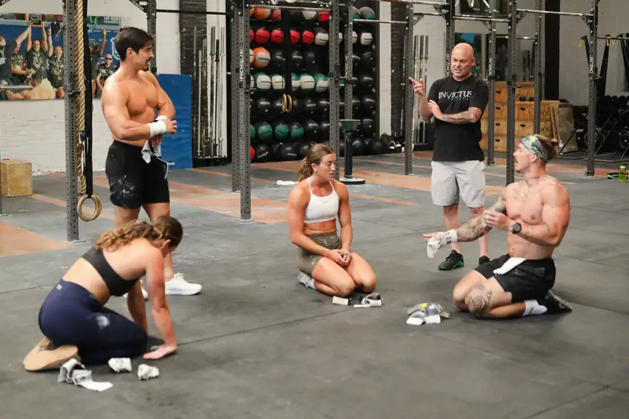Trener wyjaśnia, co to crossfit, grupie ćwiczących w siłowni.
