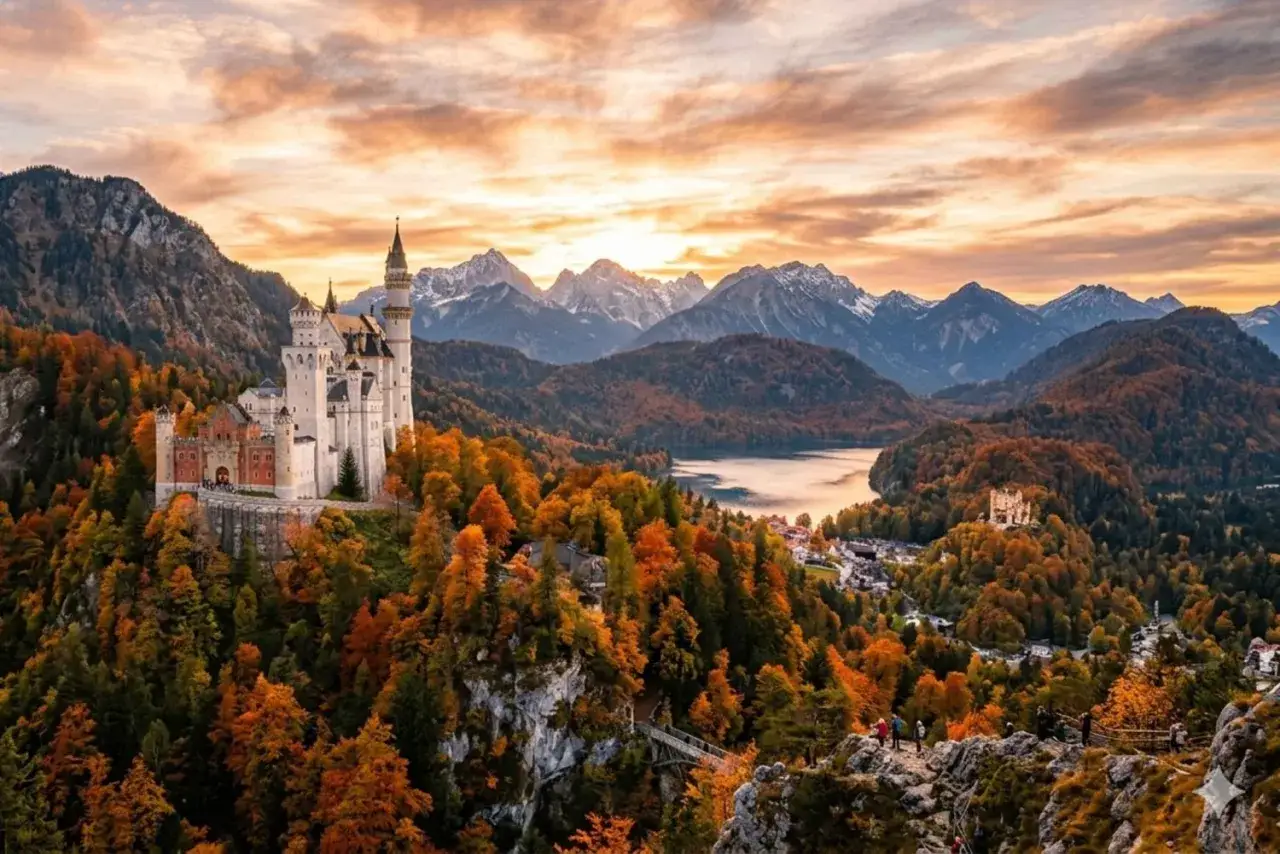 Schloss Neuschwanstein tronar över en höstfärgad skog med berg i bakgrunden.