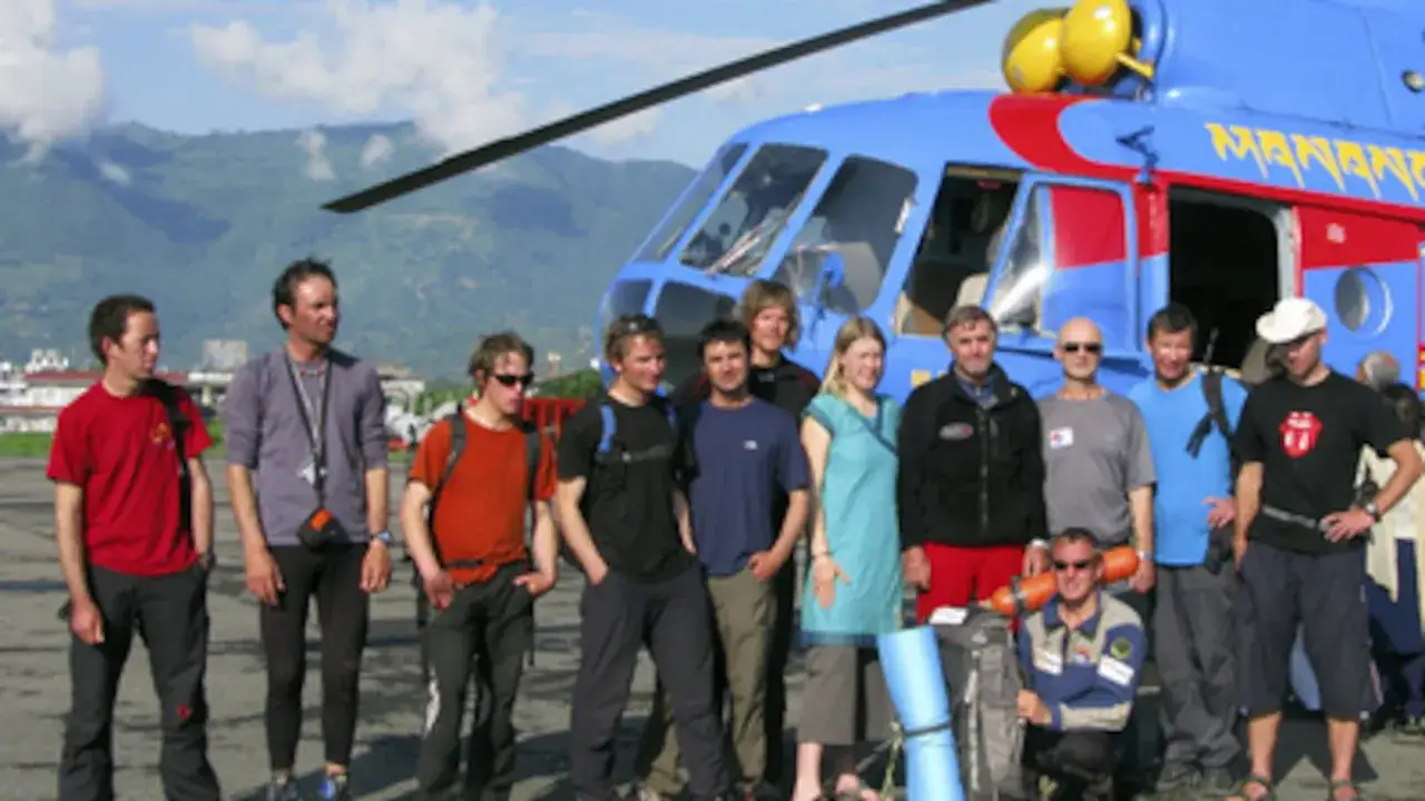 Grupo posa frente a helicóptero azul. ¡Pura vida, Iñaki! Aventura en las montañas.