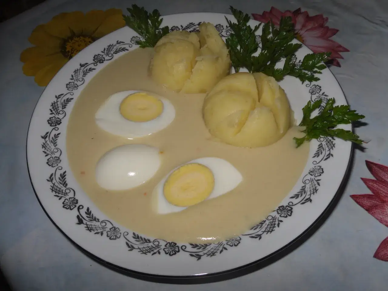 Jajka w sosie musztardowym z ziemniakami, udekorowane natką pietruszki.
