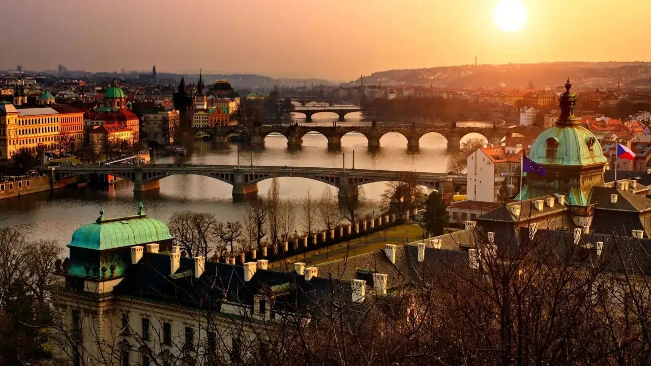 Zachód słońca nad Wełtawą, ukazujący wiele mostów i zabytkowych budynków. Praga ciekawe miejsca, które warto odkryć.