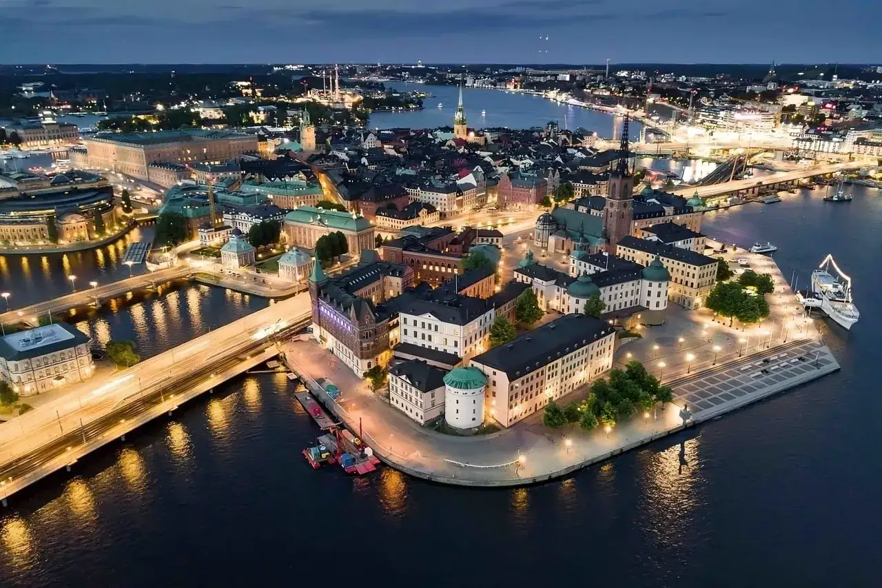 Stockholm i skymningen, med upplysta byggnader och vattenv&auml;gar. Perfekt f&ouml;r att uppt&auml;cka roliga saker att g&ouml;ra i Stockholm.