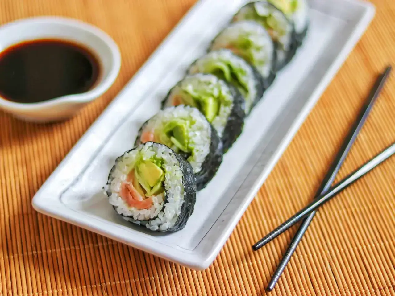 Rolka sushi z łososiem i awokado, gotowa do zanurzenia w sosie sojowym.