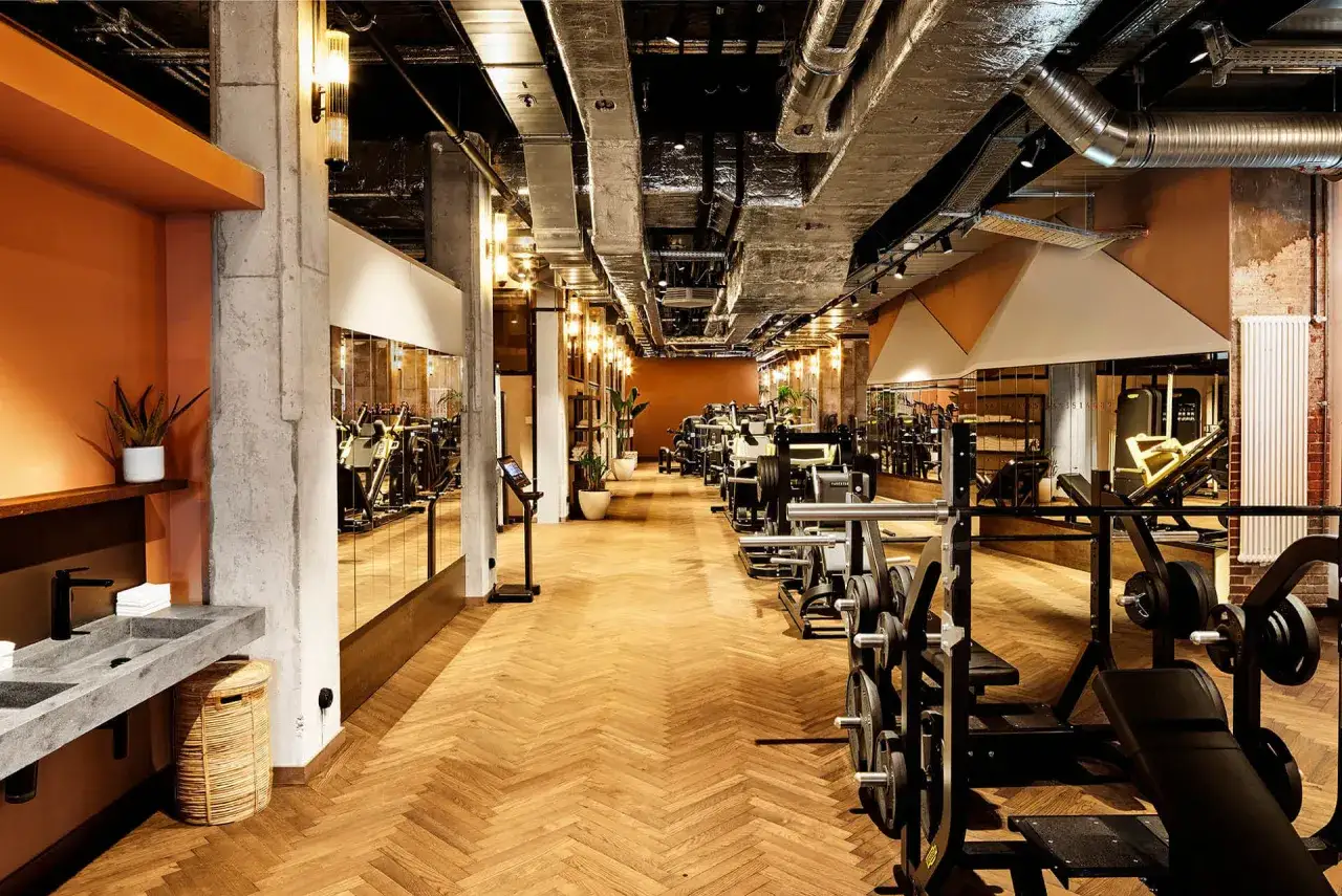 Moderne Ger&auml;te in einem stilvollen Lifestyle Club mit Holzboden und Spiegeln.