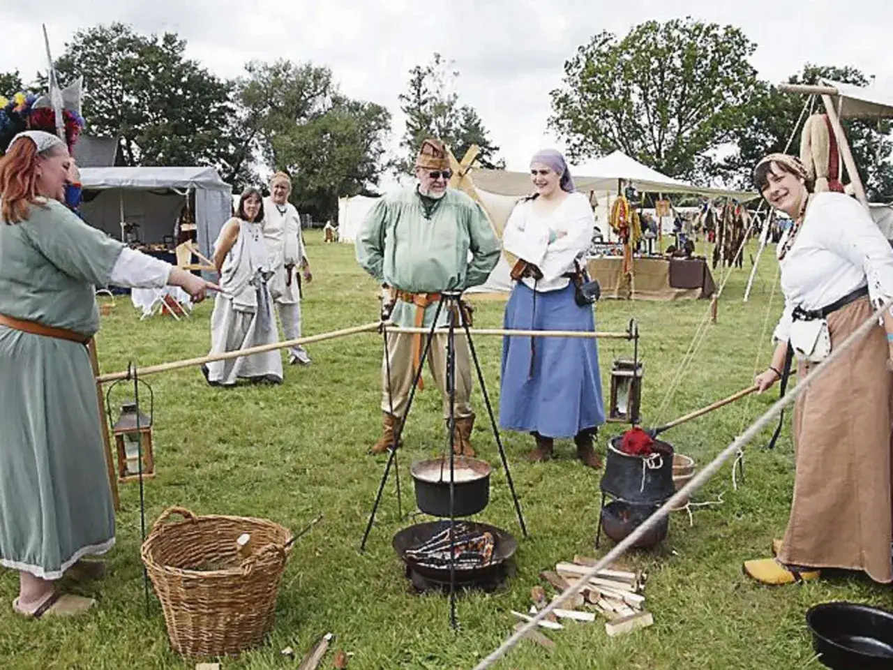 Eine lebendige Szene, die die Gesellschaft im Mittelalter zeigt. Menschen in historischen Kostümen, Lagerfeuer und Zelte deuten auf ein lebhaftes Fest oder eine Nachstellung hin.