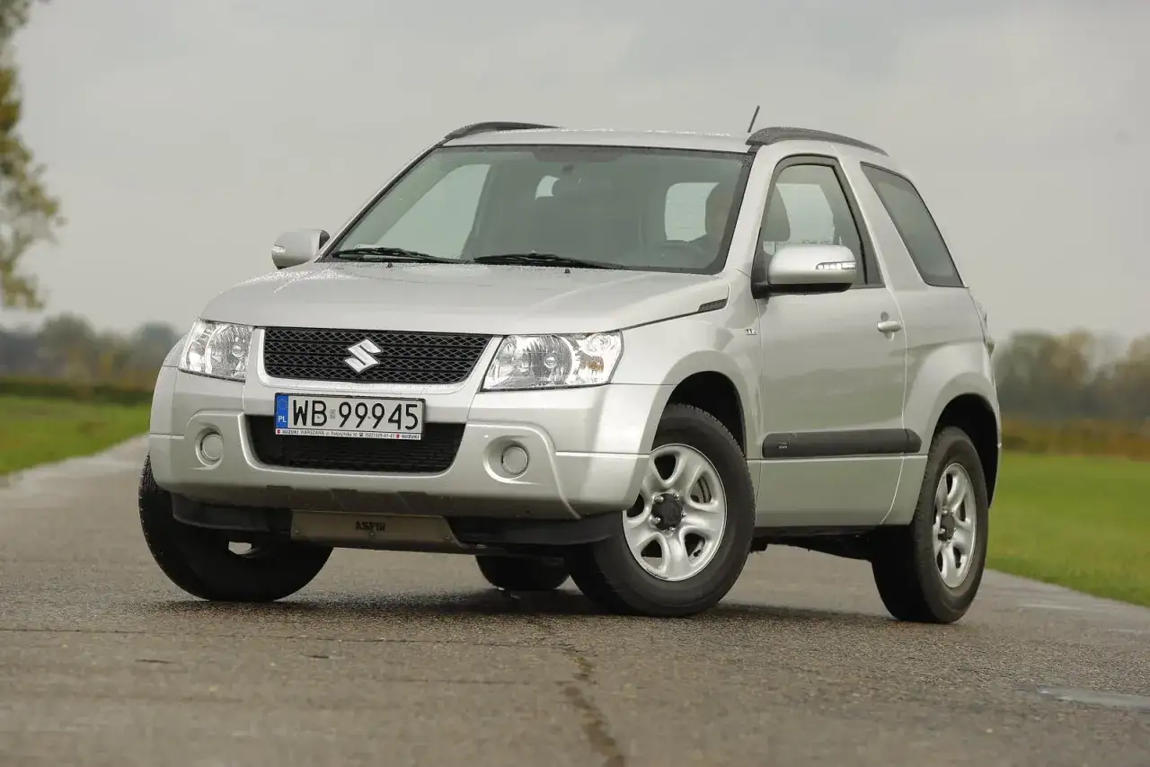 Srebrny Suzuki Grand Vitara na drodze. Poznaj jego kompaktowe wymiary i możliwości terenowe.