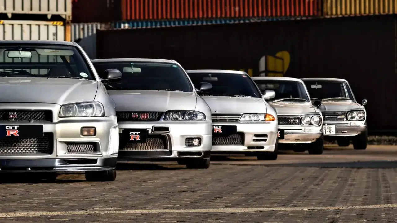 Rząd srebrnych Nissanów Skyline GT-R, od najnowszych po klasyczne, gotowych do jazdy.