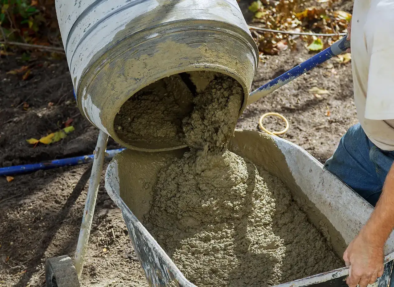 Le mortier b&eacute;ton fra&icirc;chement pr&eacute;par&eacute; coule d'une b&eacute;tonni&egrave;re dans une brouette.