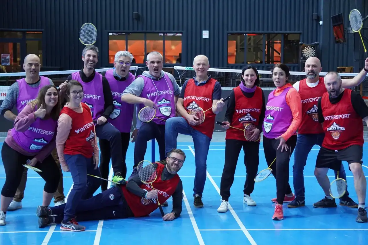 Un groupe de coll&egrave;gues s'amuse lors d'un jeu d'entreprise exemple, un tournoi de badminton amical. Ils portent des chasubles et tiennent des raquettes.