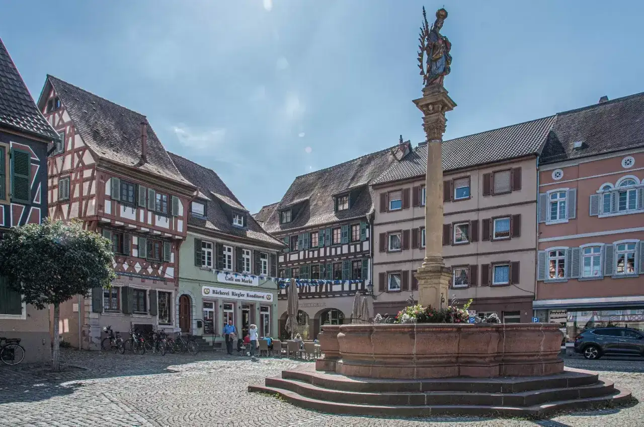 Idyllischer Marktplatz in der **Ladenburg Altstadt** mit Fachwerkhäusern, einem Brunnen und einer Statue.