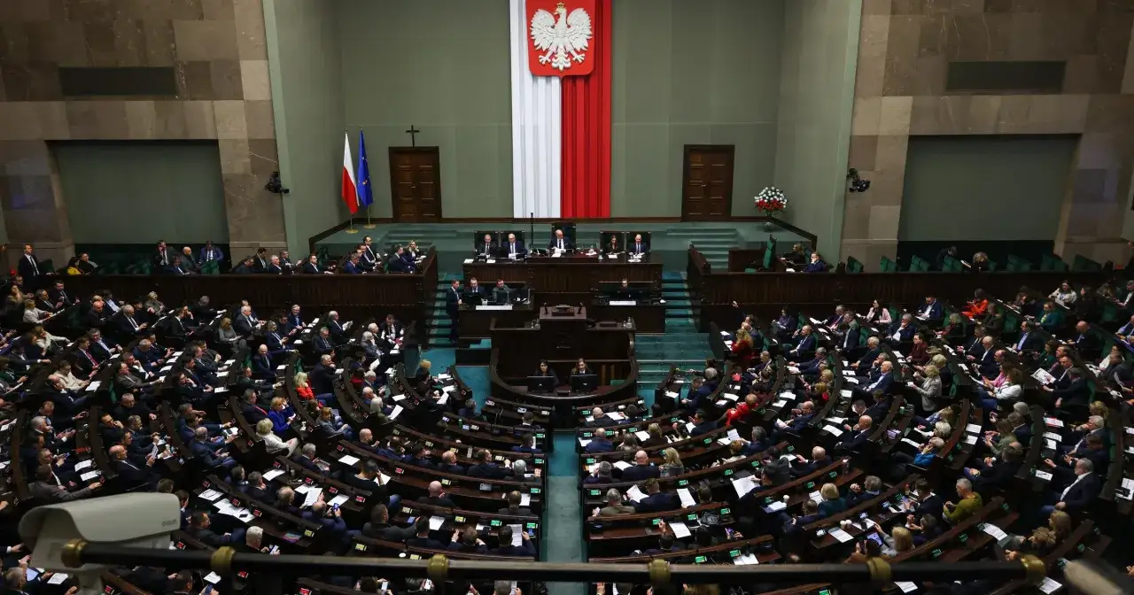 Posiedzenie Sejmu, reasumpcja obrad. Widok z góry na salę plenarną z posłami siedzącymi w ławach, biało-czerwona flaga z godłem Polski.