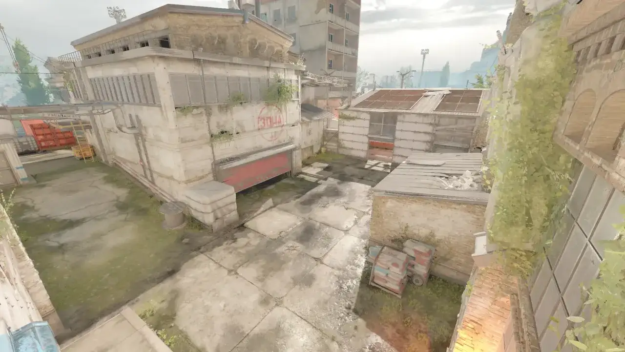 Ruiny fabryki, znane z mapy CS GO Cache, z betonowymi budynkami i zarośniętymi ścianami.