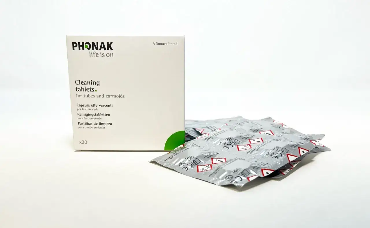 Opakowanie Phonak z tabletki do czyszczenia aparatu słuchowego i kilka pojedynczych opakowań tabletek czyszczących.