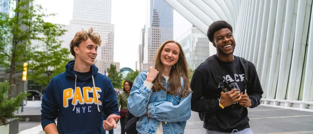 Trois étudiants souriants marchent dans les rues de New York, un rêve pour tout MBA.