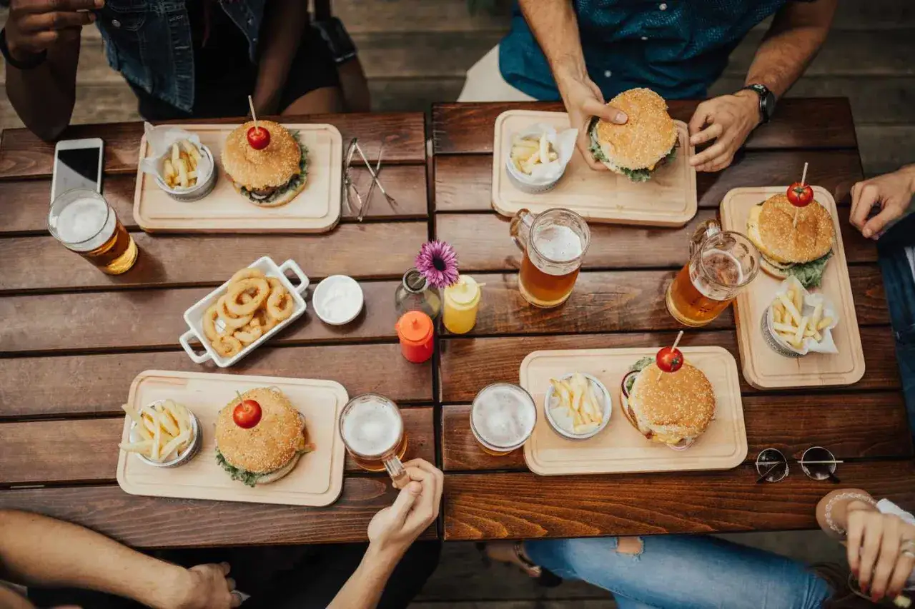 Na stole grillowe przysmaki: burgery, frytki, krążki cebulowe i piwo. Idealne menu, by zabrać na grilla!