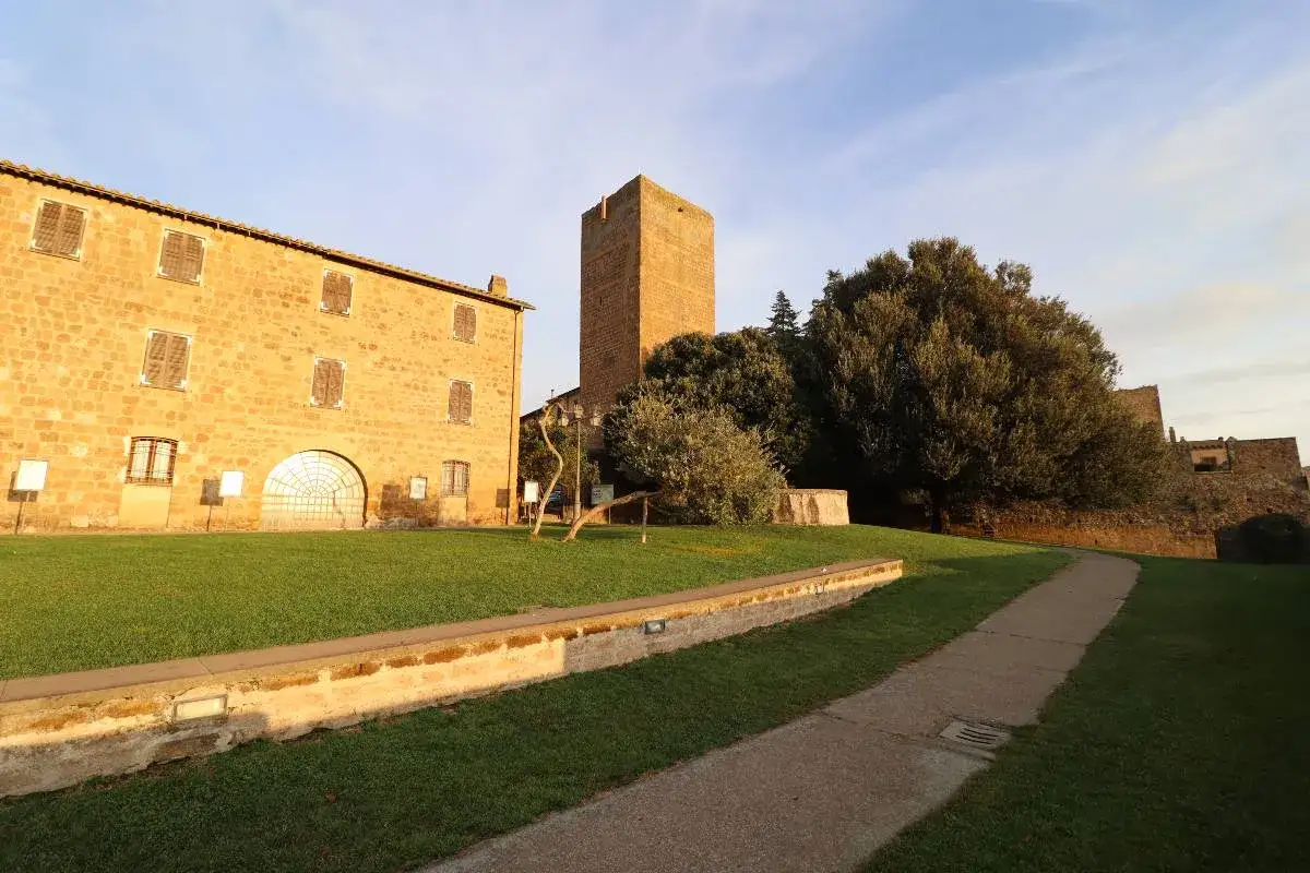 Antica torre di lavello tuscania, con edificio in pietra e prato verde.