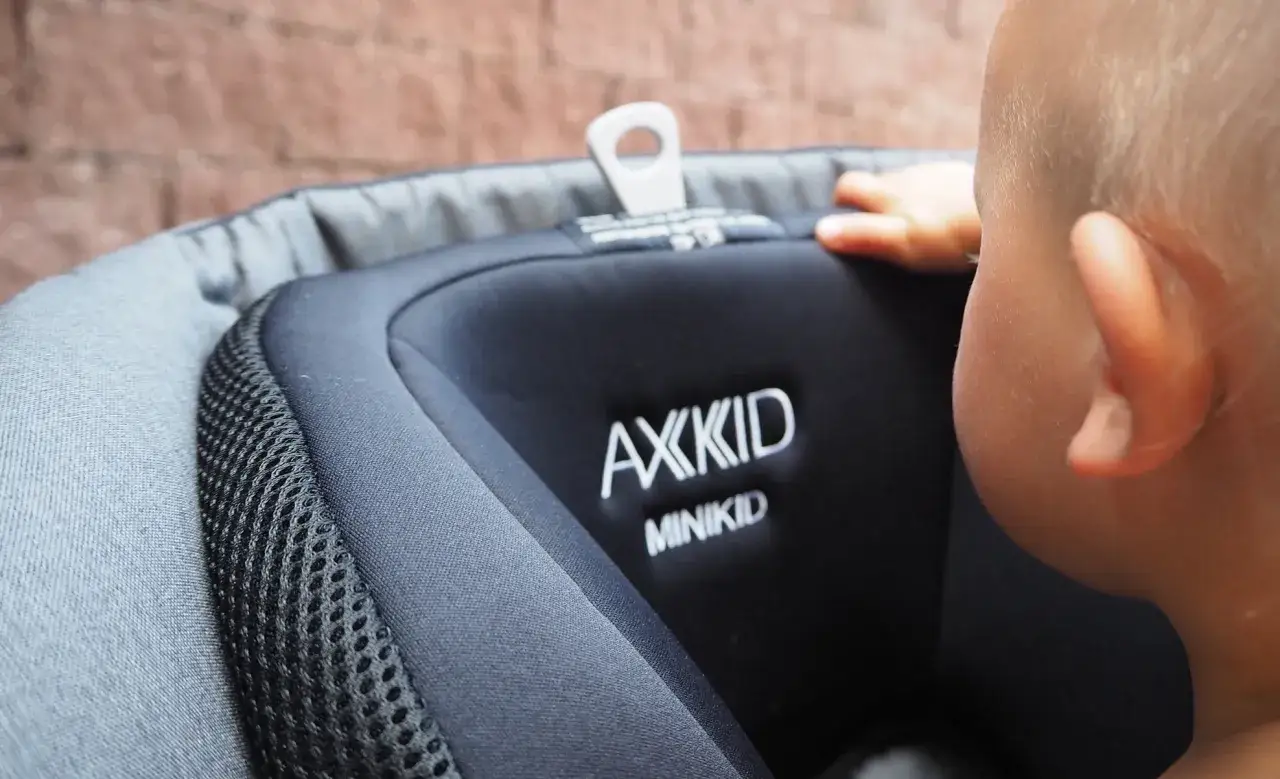 En bebis sitter i en begagnad bilbarnstol av märket Axkid Minikid.
