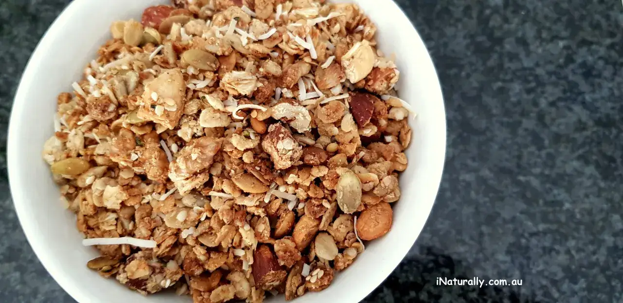 Schüssel mit selbstgemachtem, gesundem Granola, das Haferflocken, Nüsse, Samen und Kokosflocken enthält.