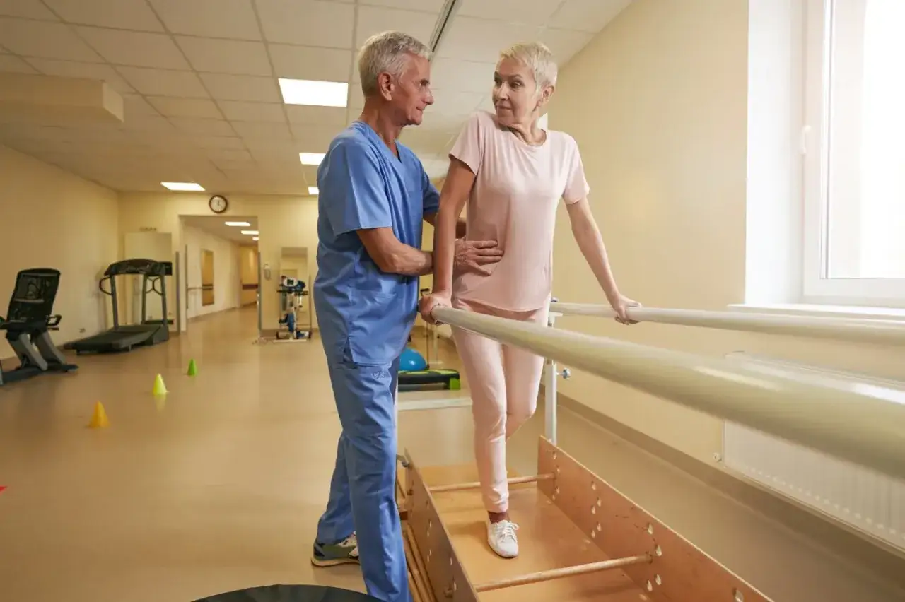 Fizjoterapeuta pomaga pacjentce w rehabilitacji na bieżni. Czy sanatorium poszpitalne jest płatne? Dowiadujemy się tego podczas ćwiczeń.
