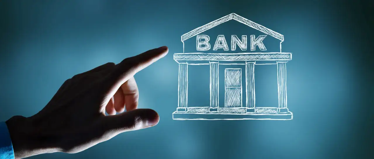 Dłoń wskazuje na szkic banku. Dowiedz się, jak odzyskać pieniądze z obligacji Getin Noble Bank.