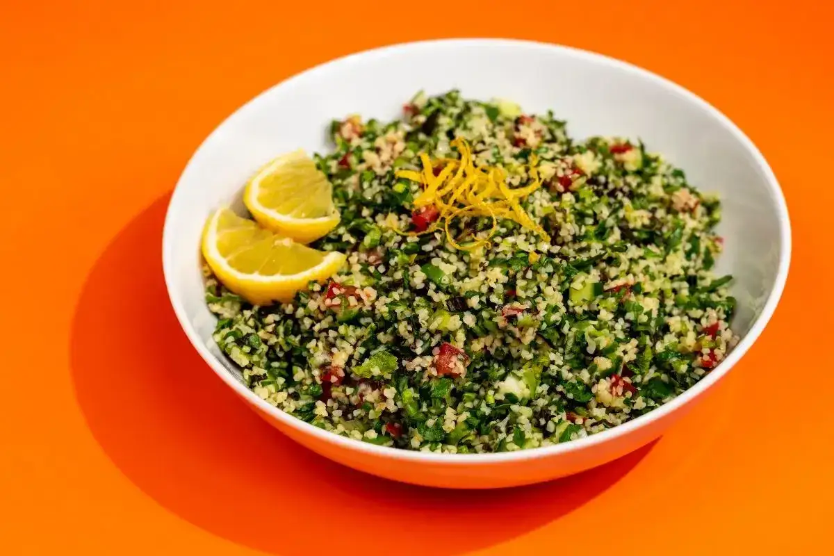 En sk&aring;l med f&auml;rsk tabbouleh, garnerad med citronklyftor och citronskal. Perfekt f&ouml;r ett l&auml;tt och smakrikt tabbouleh recept.
