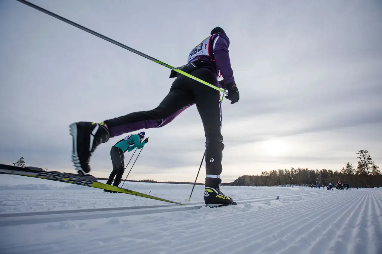 Skidåkare i Vasaloppet, med tips för att lyckas. Solen bryter igenom molnen över den snöklädda banan.