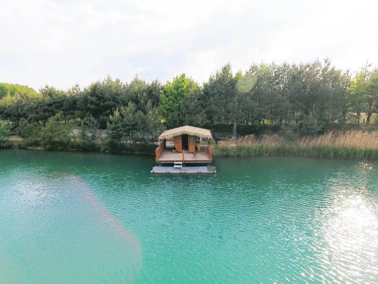 Drewniana chata na wodzie, idealne łowisko z noclegiem. Otoczone zielenią, z turkusową wodą.
