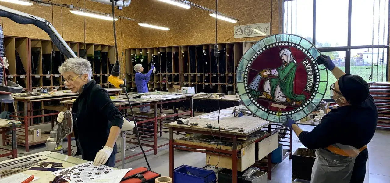 Atelier de restauration d'art, un mus&eacute;e du verre et du vitrail en pleine effervescence. Des artisans travaillent sur des pi&egrave;ces d&eacute;licates.
