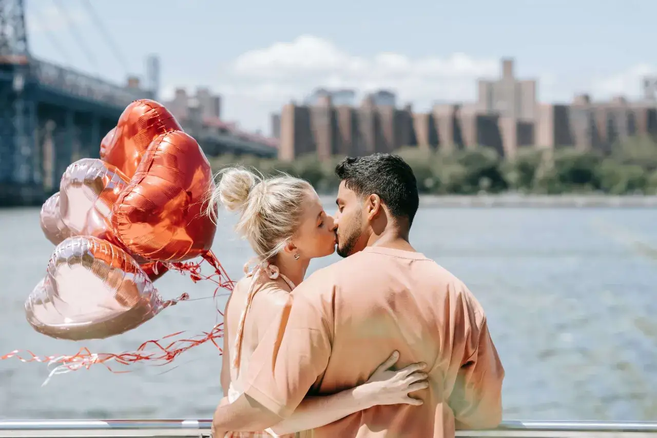 Coppia che si bacia con palloncini a forma di cuore, un'immagine che evoca la sindrome dell'innamoramento facile.