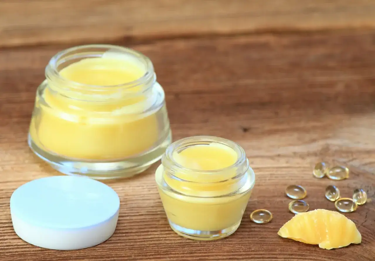 Zwei Gl&auml;ser mit selbstgemachter **anti-falten augencreme selber machen** und Kapseln auf Holzuntergrund.