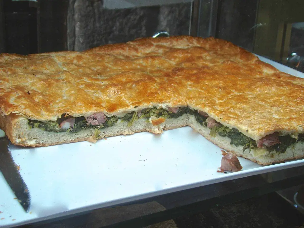 Pizza ripiena salsiccia e friarielli, con crosta dorata e ripieno verde e saporito.