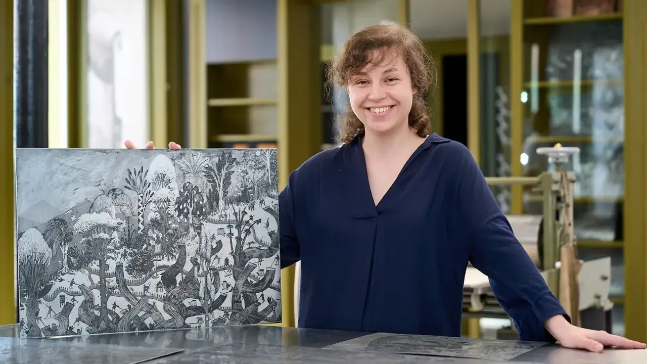 Uśmiechnięta studentka prezentuje swoją pracę graficzną, dowód talentu na studiach grafika Wrocław.