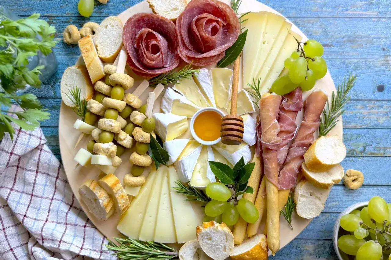 Un invitante tagliere di salumi per aperitivo con formaggi, olive, uva, pane e miele, perfetto per un momento di convivialit&agrave;.