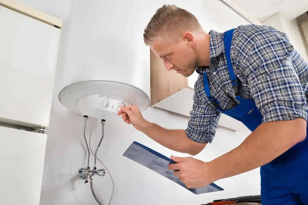 Instalator reguluje ogrzewacz wody elektryczny, trzymając w ręku dokumentację.